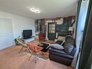 A living room with a television, a sofa, a chair, and a patterned rug. - Country house, pets welcome - 6 guests (Tavers)