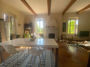 Eine geräumige Küche mit Kamin, ein Essbereich mit Musterfliesen und große Fenster für natürliches Licht.