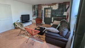 Ein Wohnzimmer mit Fernseher, einer Couch, einem Sessel und einem gemusterten Teppich.