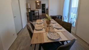 Ein Essbereich mit einem Holztisch, gedeckt für vier Personen, einer Zimmerpflanze und einem Deckenventilator.