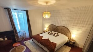 Ein Schlafzimmer mit einem großen Bett, zwei Nachttischlampen, einem Sessel und einem Fenster mit Vorhängen.