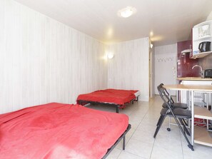 Ein Zimmer mit zwei Betten, einem Schreibtisch mit Stuhl und einer Küchenzeile.