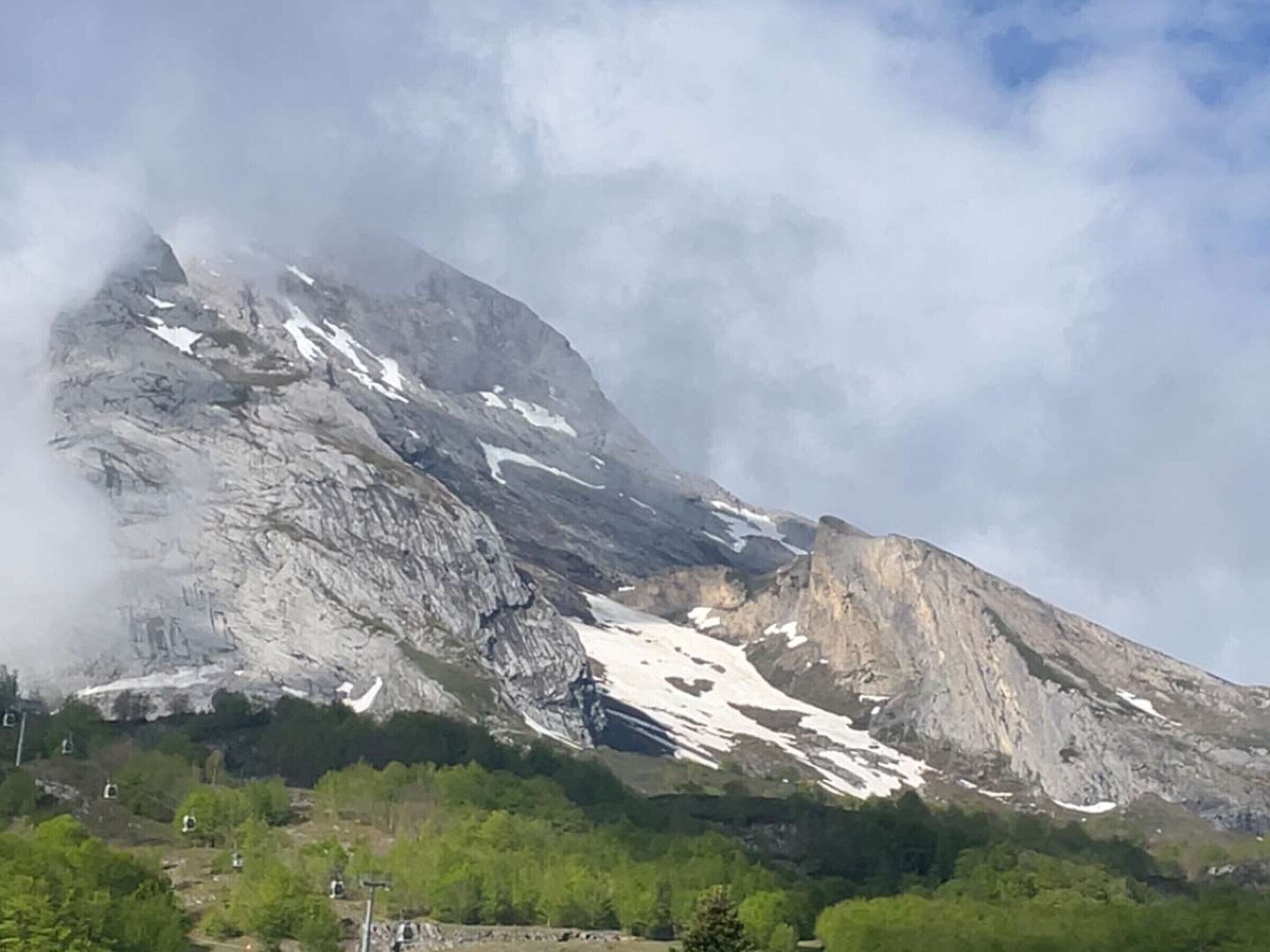 A mountain landscape with snow patches and a clear sky.