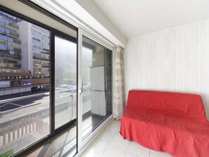 Ein Zimmer mit einer großen Schiebeglasdoor zum Außenbereich, einem roten Sofa und einer weiß-gestreiften Wand.
