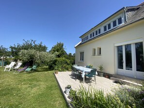Ein Haus mit Terrasse, Rasen und Garten.
