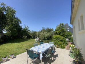 A patio with a table and chairs, surrounded by a lawn and trees. - House with garden, quiet area - Trébeurden (Trébeurden)