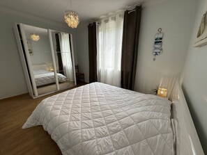 Ein Schlafzimmer mit einem großen Bett, einem Spiegel, einer Chandelier und einem Nachttisch mit Lampe.