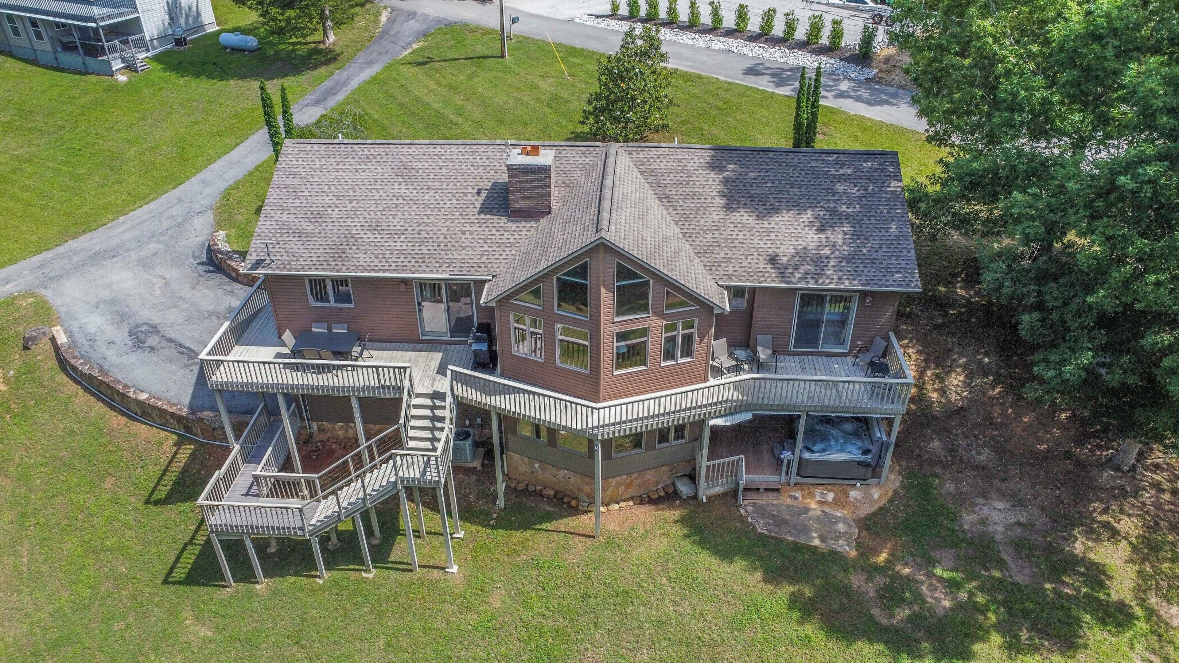A two-story house with a deck, a hot tub, and a garage.