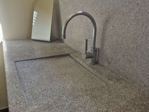 Eine Küche mit einer Granitabdeckung, einem Edelstahlarmaturenwerk und weißen Geräten.