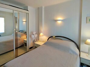 Ein Hotelzimmer mit einem Bett, einem Nachttisch, einer Lampe, einem Spiegel und einer Wandleuchte.