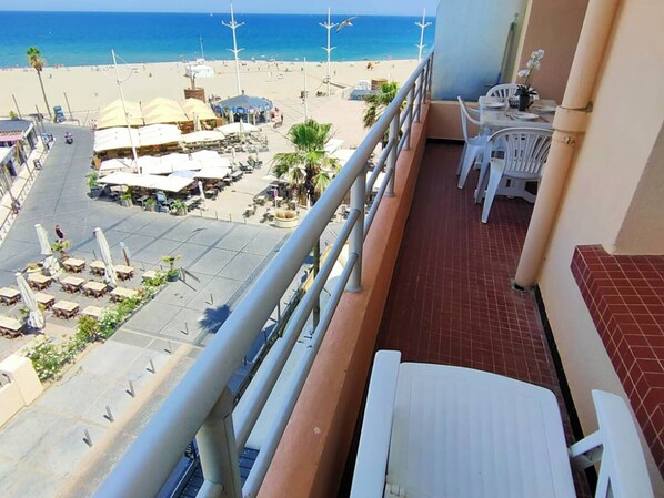 A balcony with a view of a beach, outdoor seating, and a tiled floor. - Apartment with sea view - 2 guests (Canet-en-Roussillon)