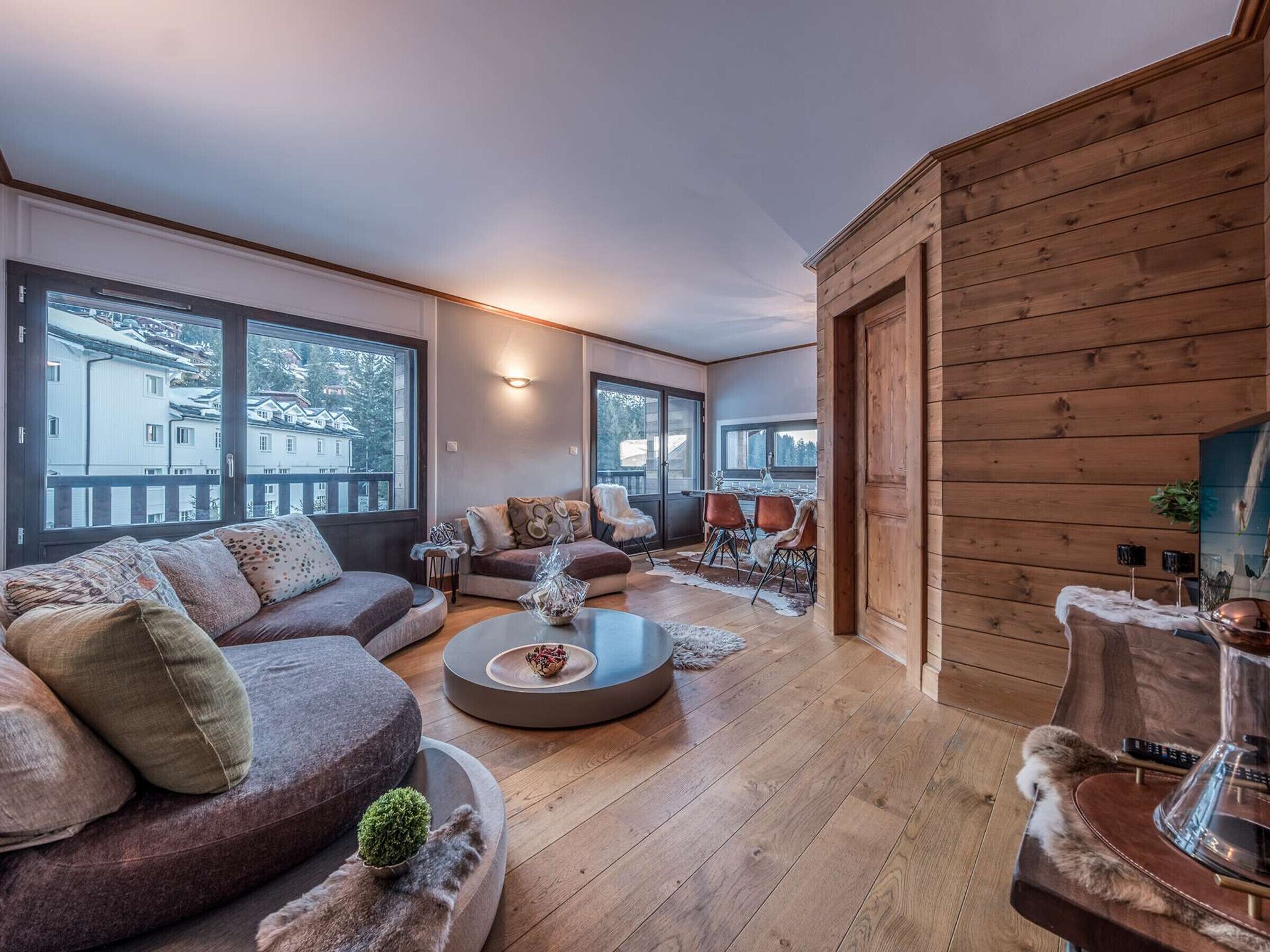 A modern living room with a large sofa, a coffee table, and a dining area with chairs.