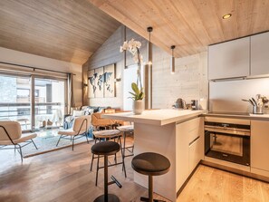Eine moderne Küche mit Holzschränken, einer Bar und einem Essbereich mit großem Fenster.