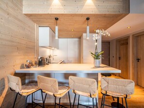 Eine moderne Küche mit Holzwänden, einer zentralen Kochinsel, Barhocker und Pendelleuchten.