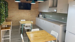 Una cocina con armarios blancos, una mesa de madera y lámparas colgantes color turquesa.