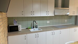 Una cocina con armarios blancos, microondas, fregadero y encimera de madera.