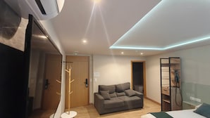 Una habitación de hotel moderna con cama, sofá, una mesita, perchero y armario.