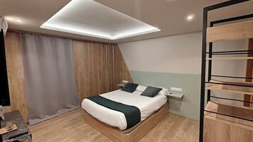 A modern bedroom with a bed, a bedside table, a wall-mounted shelf, and a ceiling light fixture.
