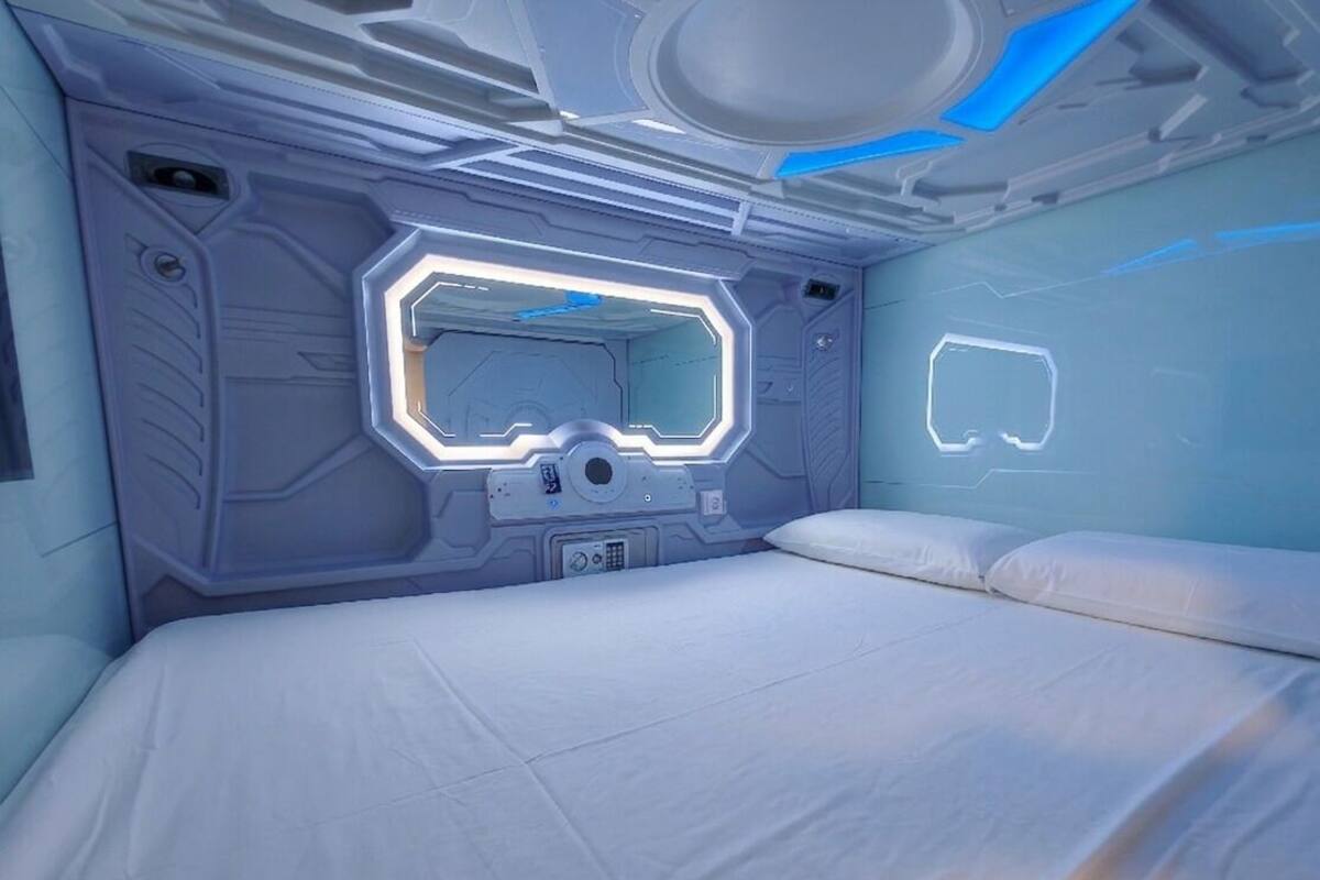 Una habitación futurista con un panel de control central, una cama y una pantalla montada en la pared.