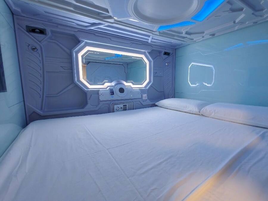 Una habitación futurista con un panel de control central, una cama y una pantalla montada en la pared.