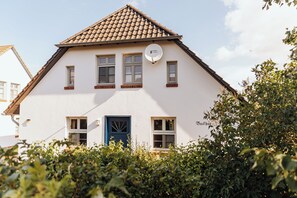 A two-story building with a white facade, a blue door, and a satellite dish. - Backhus Vacation Home: Country House with Garden. Ideal for large families (Mellenthin)