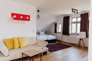 Ein modernes Schlafzimmer mit einem Bett, einer Couch, einem Sessel und einem Fenster mit Vorhängen.