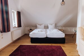 A bedroom with a double bed, a red rug, a window with curtains, a radiator, and a hanging light fixture. - Backhus Vacation Home: Country House with Garden. Ideal for large families (Mellenthin)