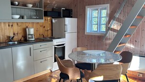 Puinen sisustus, jossa on keittiö, ruokailutila ja portaikko.
