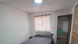 A bedroom with a bed, a window with curtains, a wooden wardrobe, and a herringbone-patterned floor. - "Sleeping Woman" Accommodation (Ambuquí)