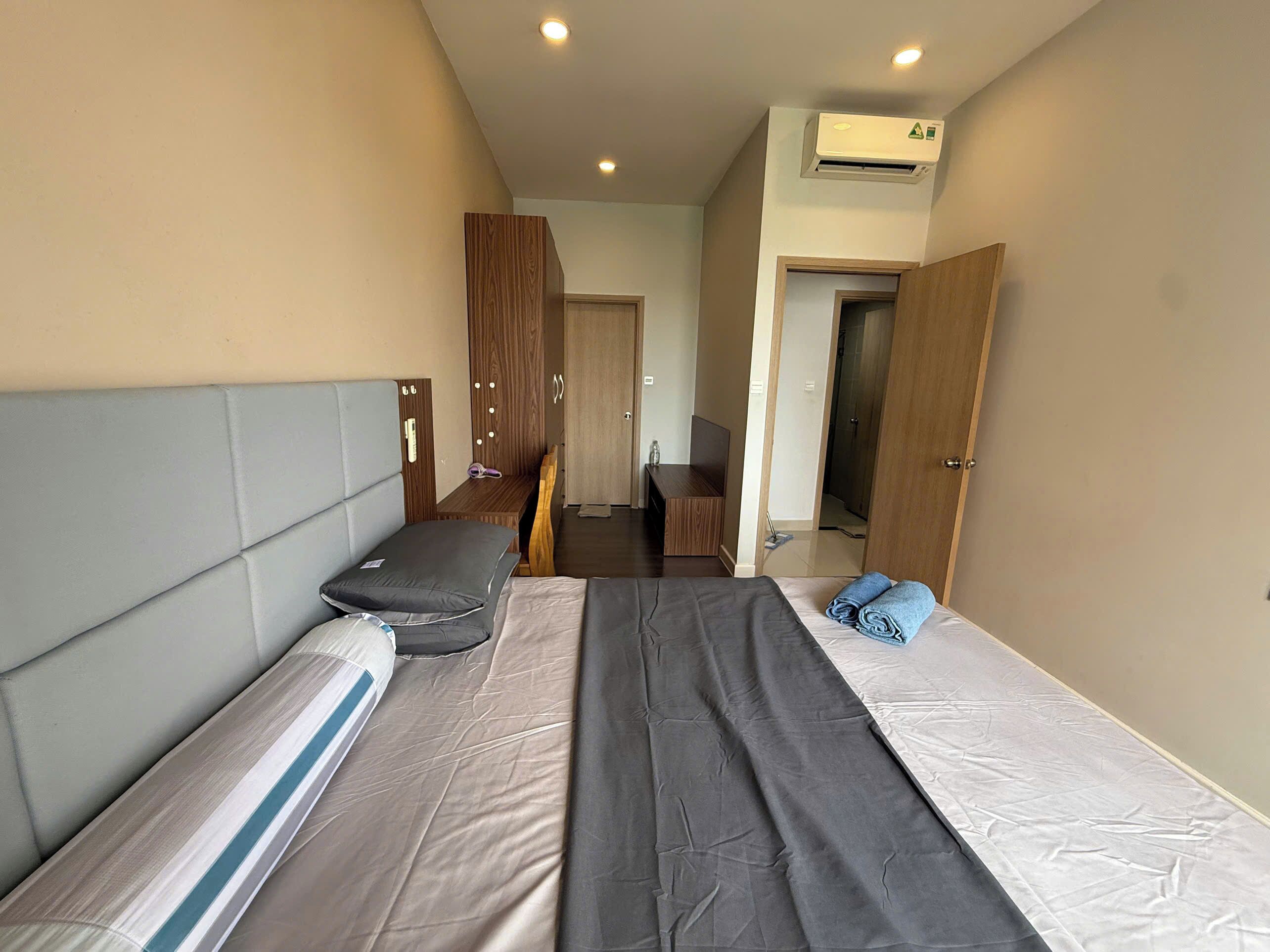 Una habitación de hotel con cama, escritorio, armario y aire acondicionado.