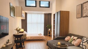 Una habitación de hotel moderna con cama, sofá, televisión y una pequeña mesa con vela.