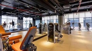 Un gimnasio con equipamiento de ejercicio, amplias ventanas y un diseño moderno e industrial.