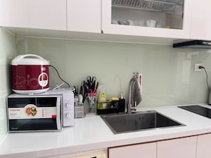 A kitchen with a microwave, rice cooker, and sink. - The Sun Avenue  luxury Apartment (Thanh Ho Chi Minh)