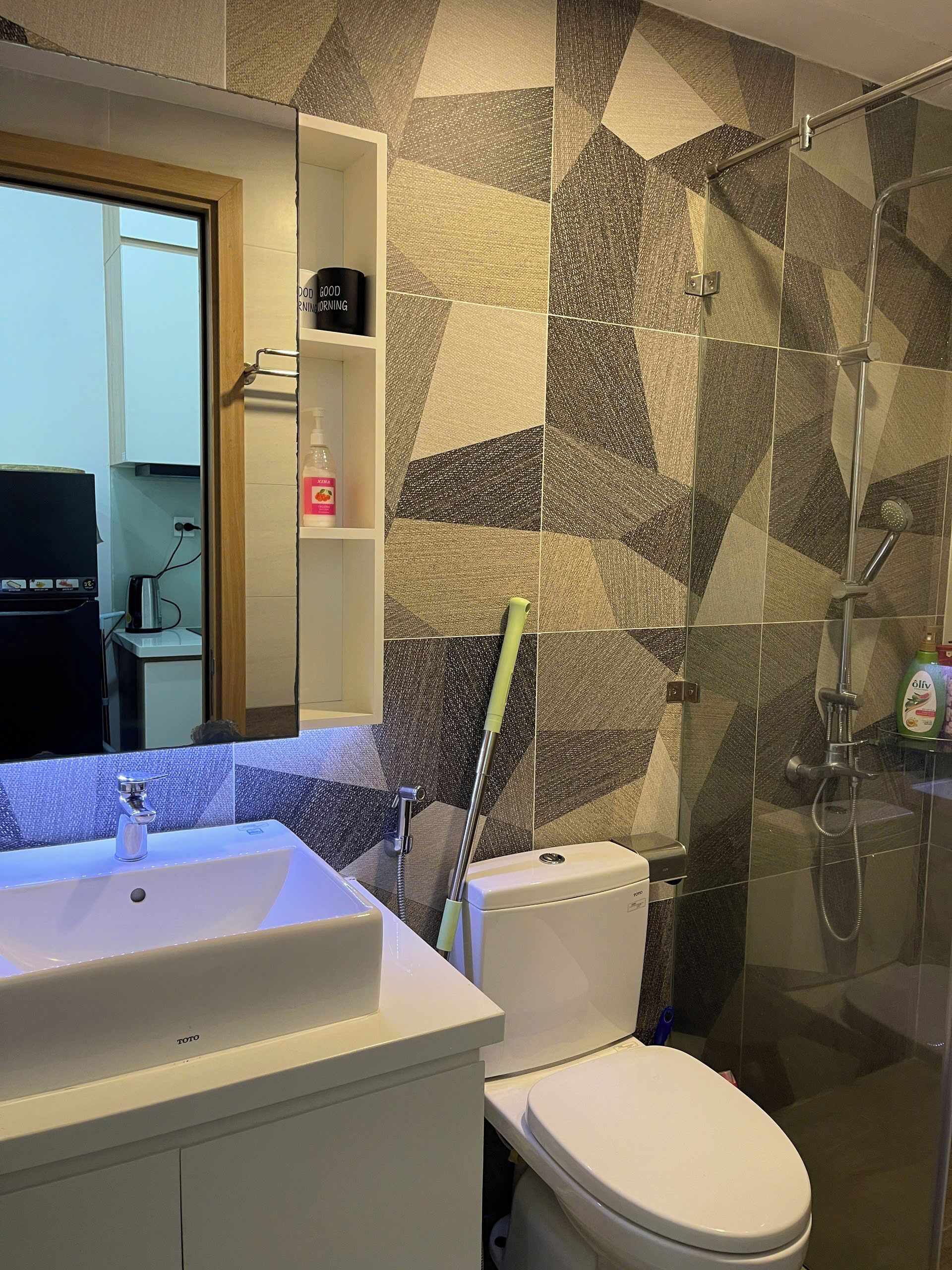 Un baño con lavamanos, inodoro y ducha blancos.
