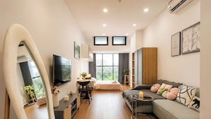 Una sala de estar moderna con sofá, televisor, comedor y un amplio ventanal.
