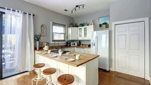 Eine moderne Küche mit einer Holztheke, weißen Schränken und einem Kühlschrank.