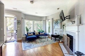 Ein geräumiges Wohnzimmer mit einem blauen Sofa, einem Kamin und großen Fenstern.