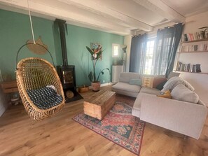 Ein gemütliches Wohnzimmer mit einer Couch, einem Hängesessel, einem Kamin und einem Bücherregal.