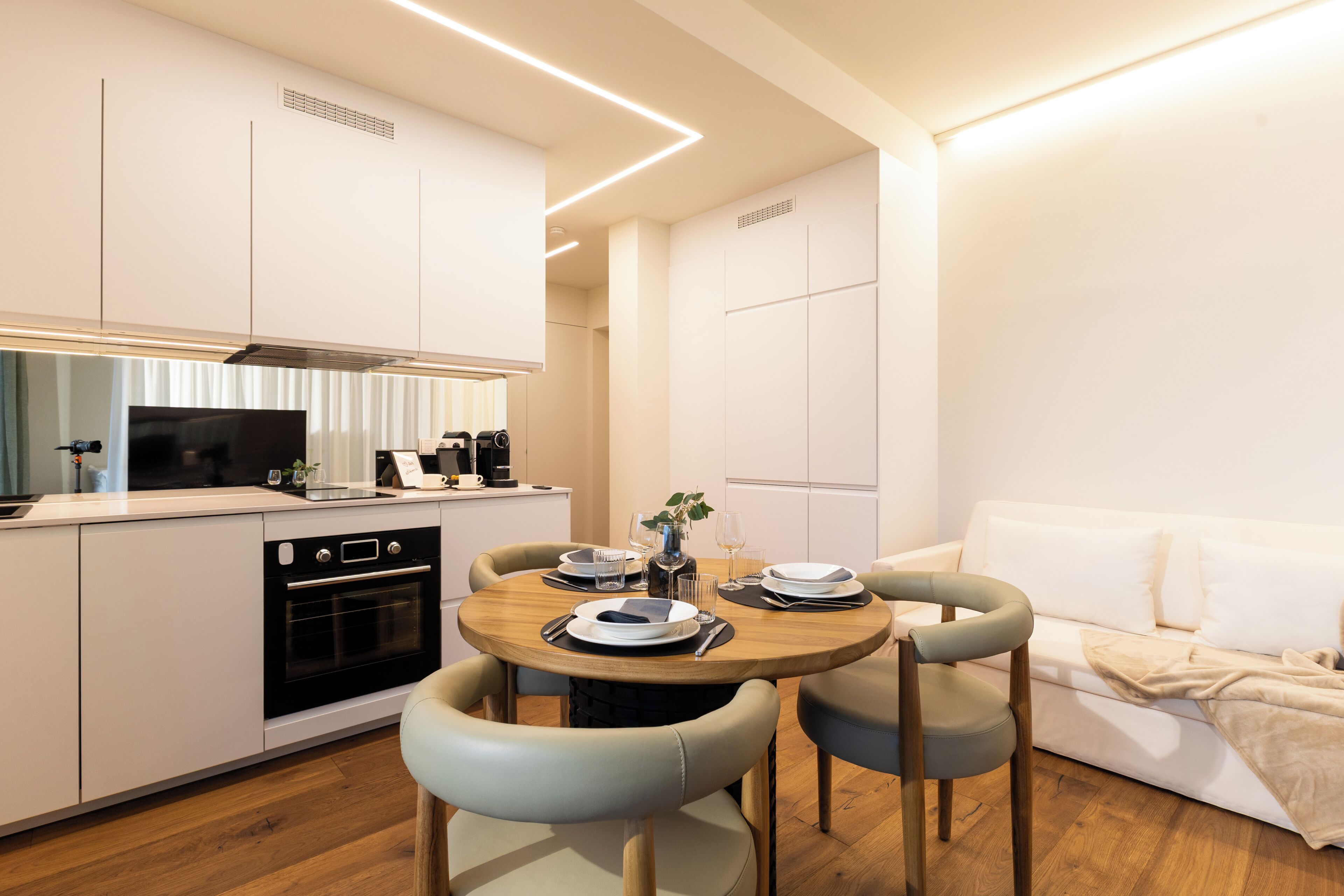Une cuisine moderne avec un coin repas, des meubles blancs et une table à manger en bois avec des chaises.