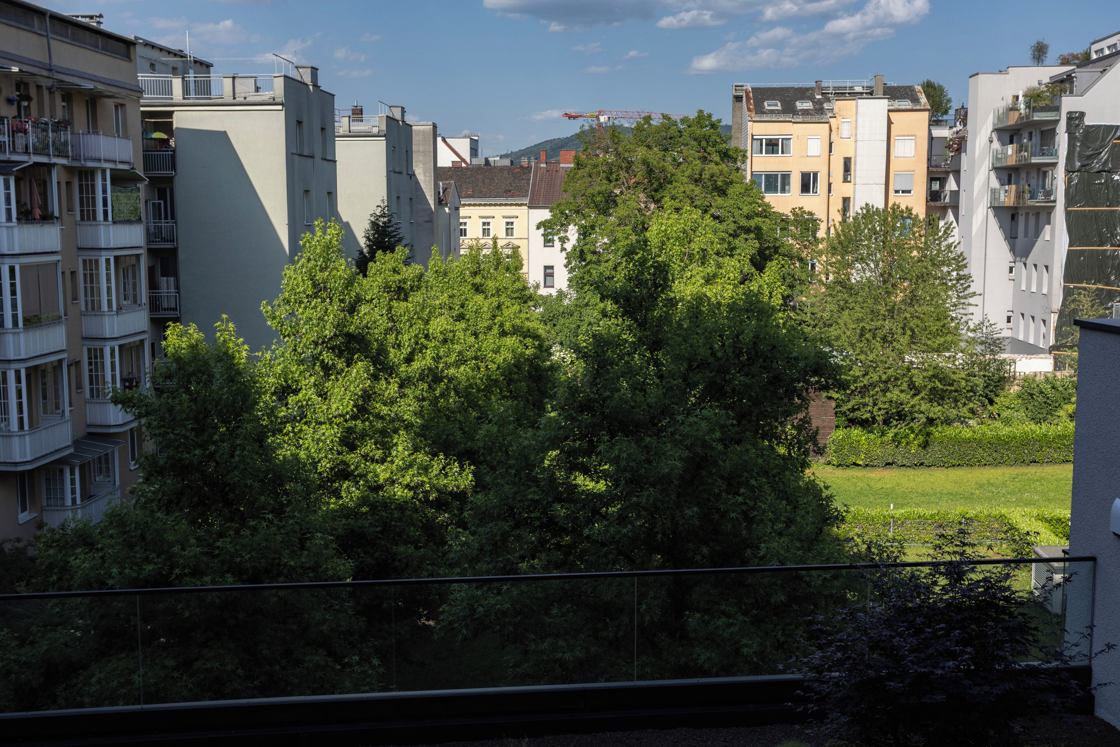 Ein Wohngebiet mit mehrstöckigen Gebäuden, einem grünen Park und einem Kran in der Ferne.