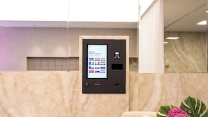 Un espace d’accueil doté d’un kiosque numérique, d’un coin salon confortable et d’un vase rempli de fleurs.