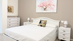 A bedroom with a bed, a nightstand, a dresser, and a wall-mounted painting. - SE276 - Senigallia, elegant apartment with a/c close to all main services (Senigallia)