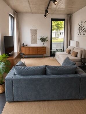 A modern living room with a grey sofa, wooden sideboard, and a television. - Stylish Antwerp City Centre Apartment with Garden & Parking (Antwerpen)