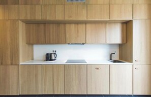 Eine K üche mit Holzausstattung, einer weißen Arbeitsplatte, einem Wasserkocher und einem Spülbecken.