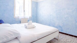 Een slaapkamer met een bed, een raam en een wand met een structuur.