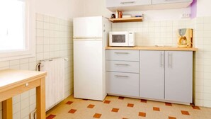 Een kleine keuken met een koelkast, magnetron en een houten aanrecht.
