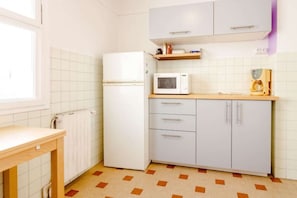Une cuisine compacte équipée d’un réfrigérateur, d’un four à micro-ondes et d’un plan de travail en bois.