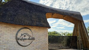 A building with a thatched roof, a brick wall, and a logo with a house and mountains.