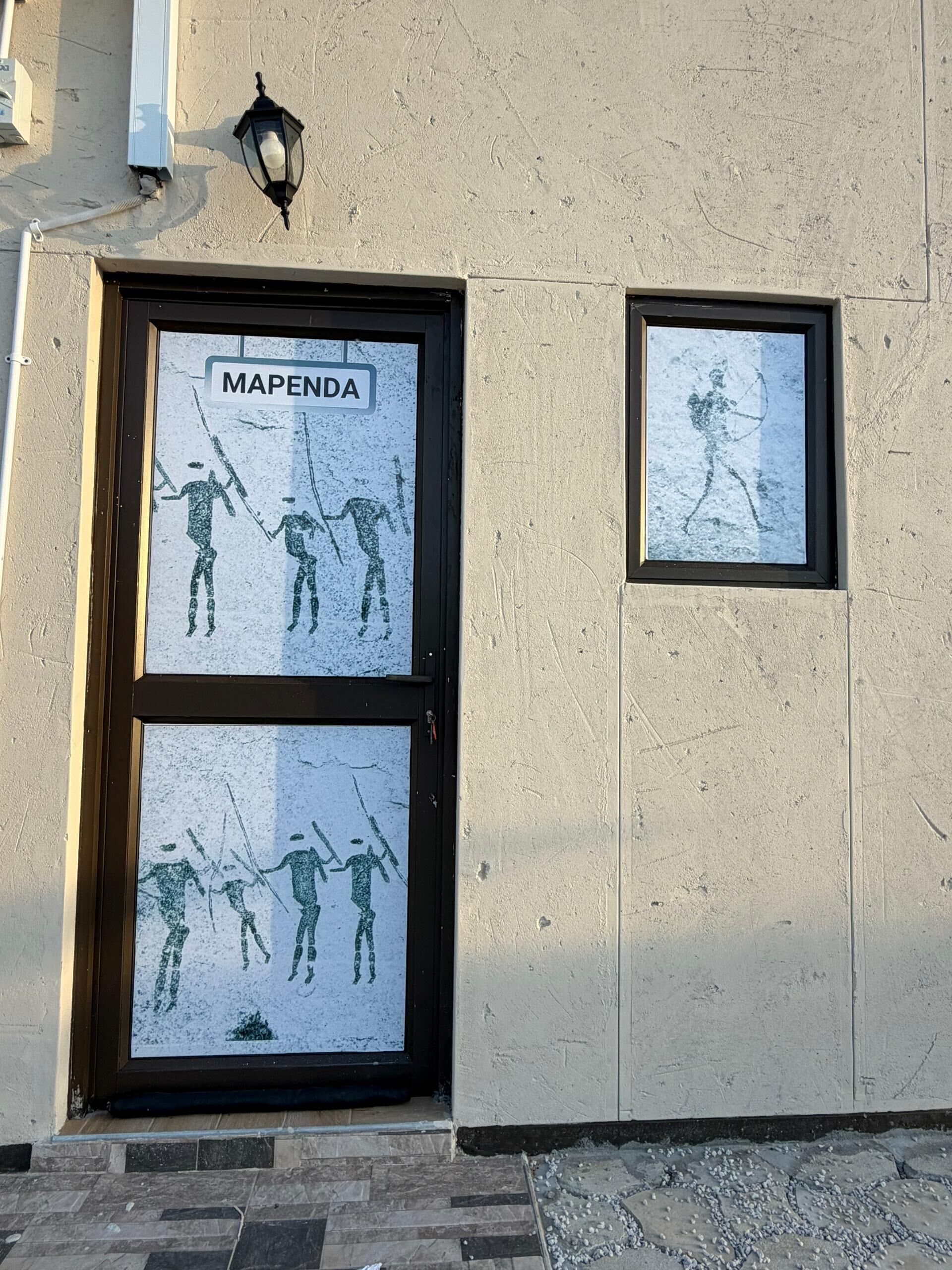 Fachada de edificio con un ventanal enmarcado que muestra un mapa y dos ventanas más pequeñas con siluetas.