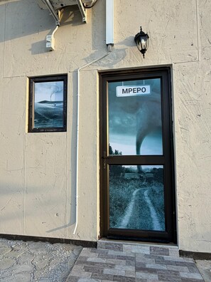 A building with a sign reading 'MPEPO' above a door, a small window with a picture of a landscape, and a wall-mounted light fixture. - Watupa Chalets (Rundu)